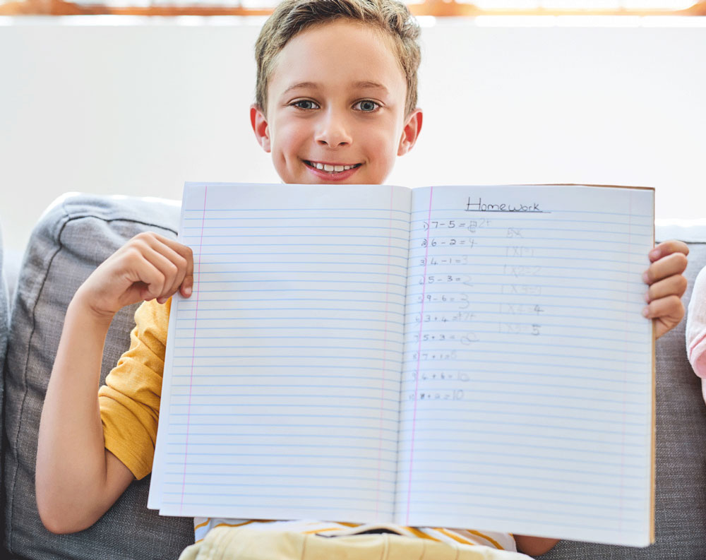 Enfant content montrant sson cahier de devoir
